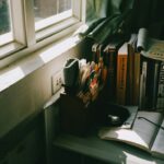 窓辺の机に置かれた本と眼鏡を写したイメージ写真。有栖川有栖本人の写真ではありません